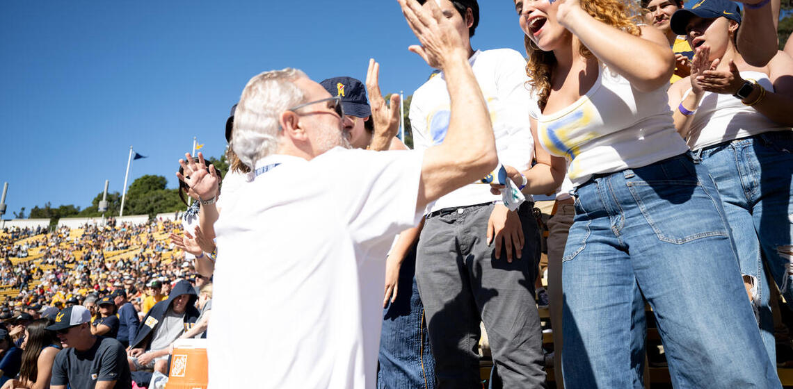 student interacting with rich lyons in a football game